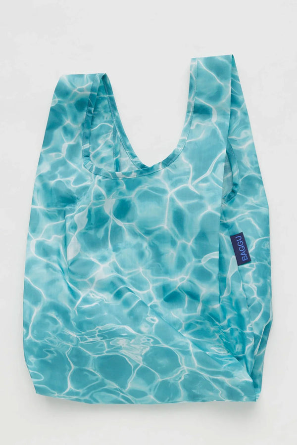 Small reusable shopping back that features a blue reflective water pattern from a pool. White background.