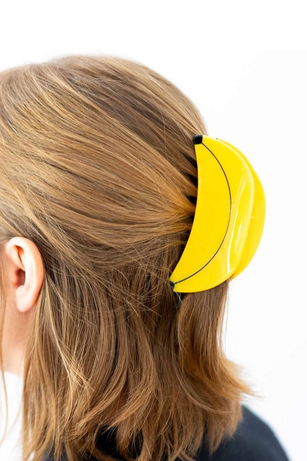 Person wearing yellow banana shaped hair claw in their hair.