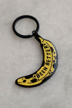 Enamel keychain with black hardware of a banana with black spots. The banana says Been Better in black text.