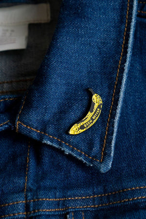 Yellow bruised banana enamel pin. The banana has Been Better in yellow text on it. The pin is on a denim lapel.