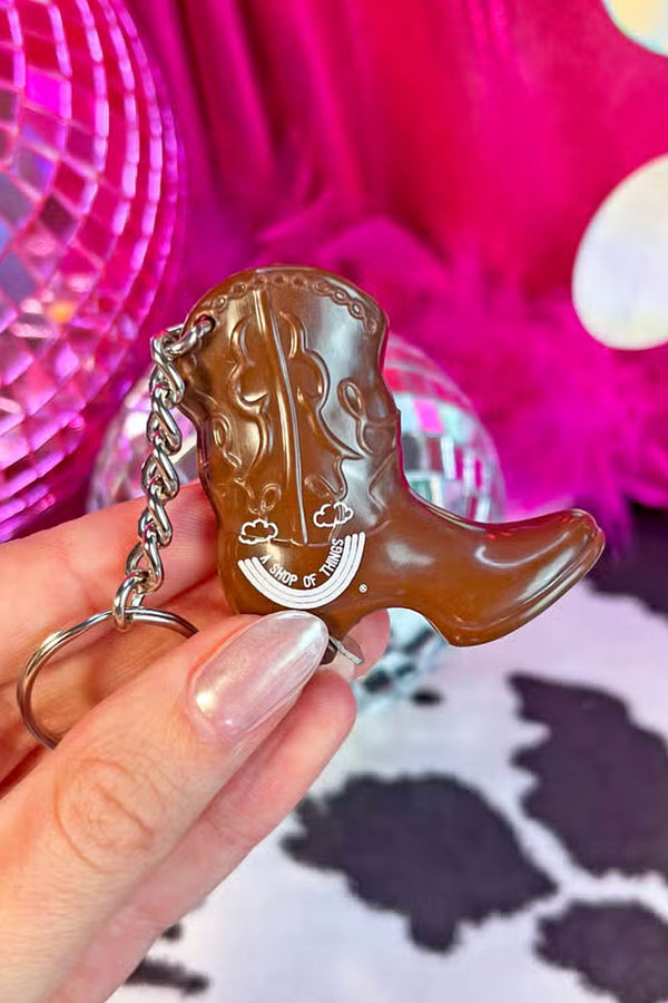 A person holding a Plastic cowboy boot shaped bottle opener with silver keychain.