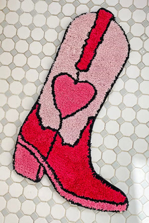 Pink western style cowboy boot rug with a heart in the center. White tile background.