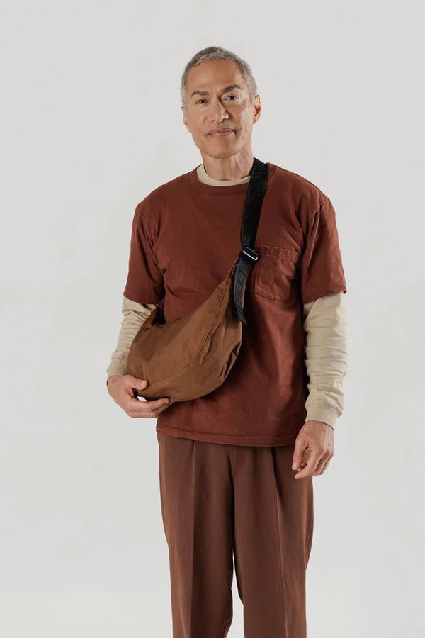 Person wearing brown crescent bag across their chest.