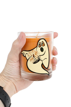 Person holding a clear scented candle jar with a ghost holding a candle on the front of it. White background.
