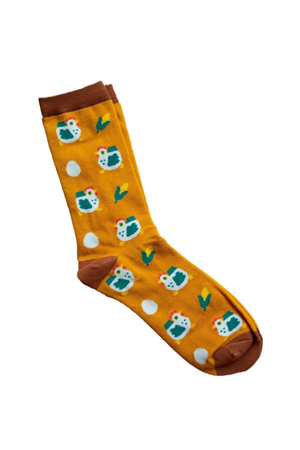 Orange socks with a brown toe and heel. Brown band at the top. Socks have white and green chickens, ears of corn, and eggs printed all over them.