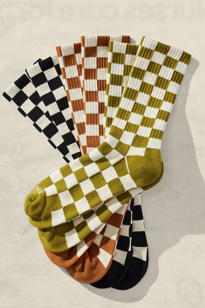 A pile of Checkerboard crew socks in cream and cactus green, brown, and black.
