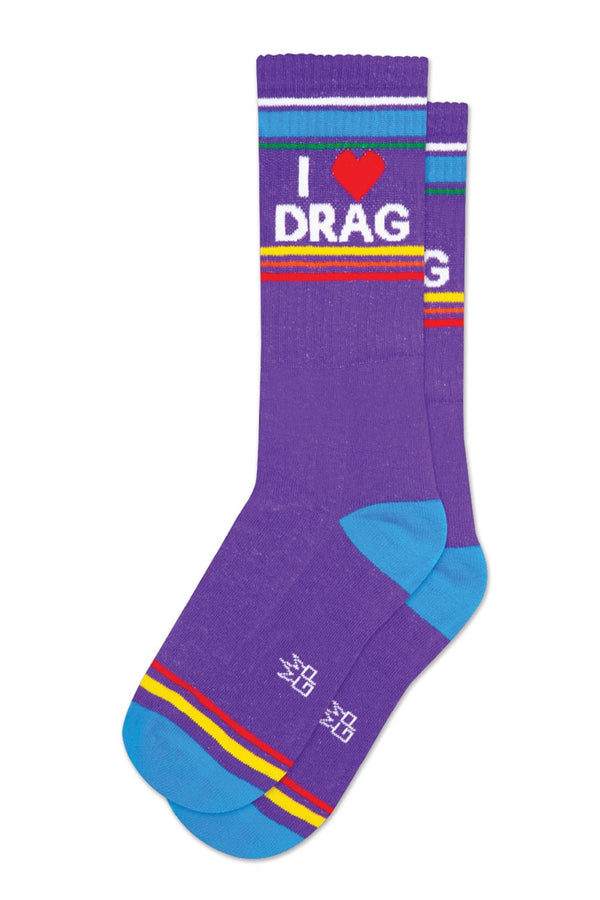 One pair of purple mid calf athletic socks with a blue heel and toe. Across the toes there is yellow and red stirpes. Across the top there is White, blue, green, yellow, pink, and red stripes. The socks say I Heart Drag in white lettering. white background.