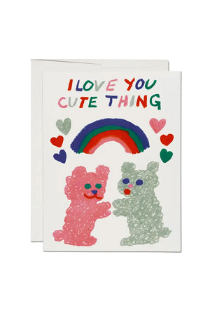 White greeting card of a blue, green and red rainbow surrounded by hearts. Below the rainbow are two fluffy animals in pink and green reaching out to each other. The card says I Love You Cute Thing.