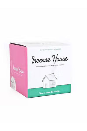 Packaging for house incense burner. The box is white with a pink side and green strip across the bottom. The box features an illustration of the house incense burner. It says Incense House in black cursive font.