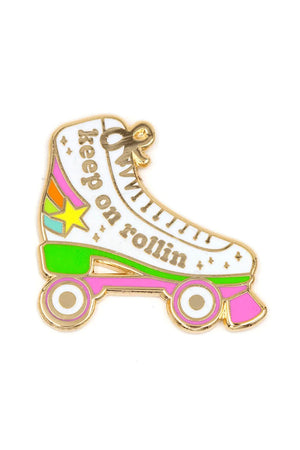 Enamel pin of a white roller skate with pink wheels and a rainbow with a star at the heel. The pin says Keep on Rollin. White background.