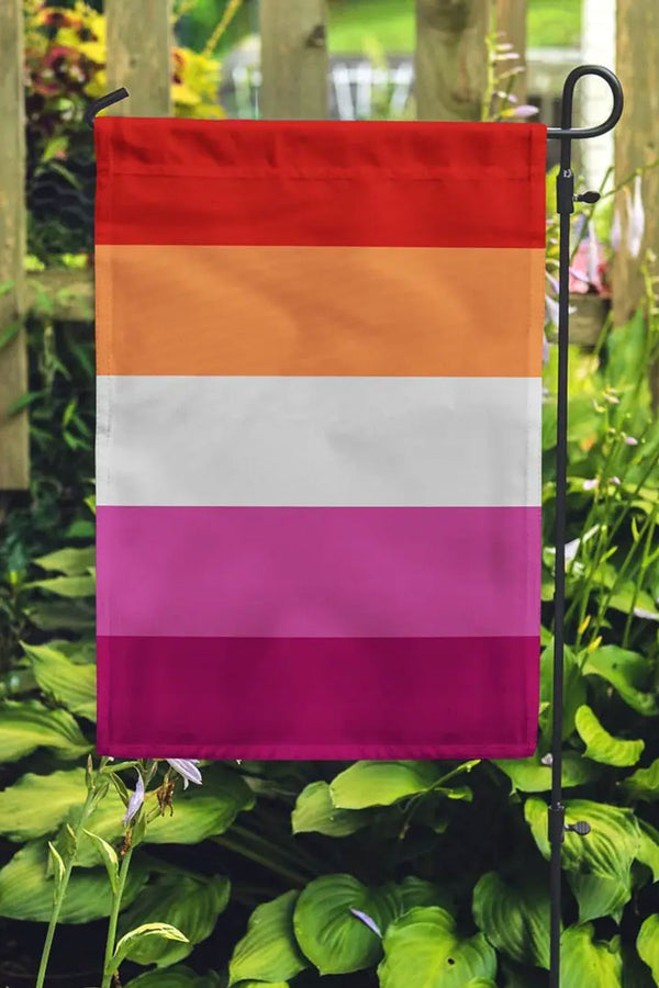 Lesbian Pride flag hanging on a garden flag pole. The flag consists of 5 horizontal stripes of Red, orange, white, pink , and dark pink.