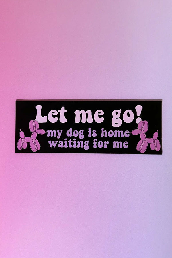Black car magnet against a pink and purple gradient background. The magnet says "Let Me Go! My dog is home waiting for me"  in pink bubble text. On either side of the text is an illustration of a pink balloon dog.