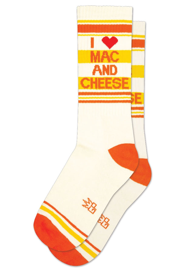 One pair of white athletic socks with a red heel and toe and yellow and red stripes across the top and across the toes. The socks say in Red lettering I Heart Mac And Cheese.White background.