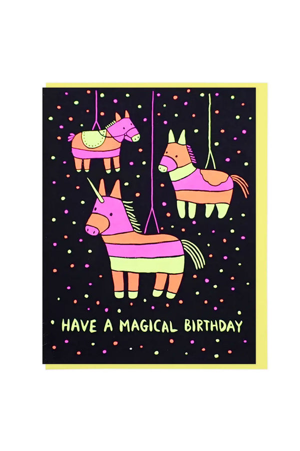 Black greeting card with yellow envelope. The card features illustration of three yellow, pink, and orange donkey pinatas surrounded by confetti. Underneath the pinatas the card says Have a Magical Birthday. White background.