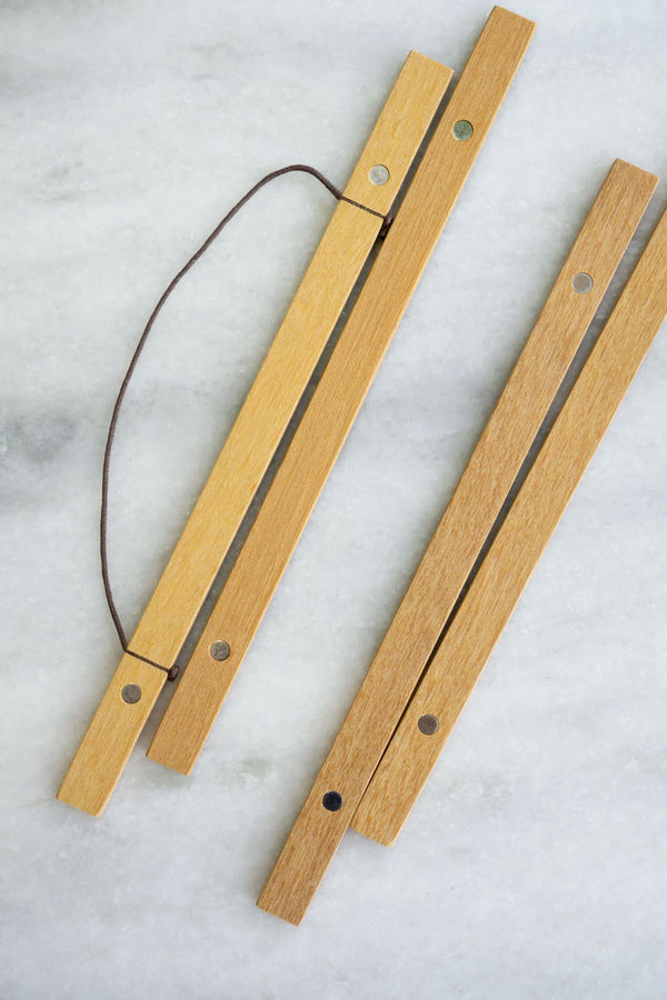 The top and bottom parts of a magnetic wooden frame that hangs from walls. White marble background.