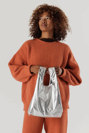 A person holding a Silver metallic reusable tote bag.