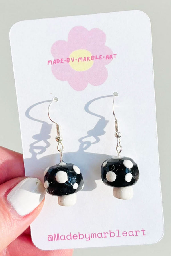 Handmade black and white polymer clay mushroom earrings. The mushrooms are attached to dangly earrings with jump ring. 