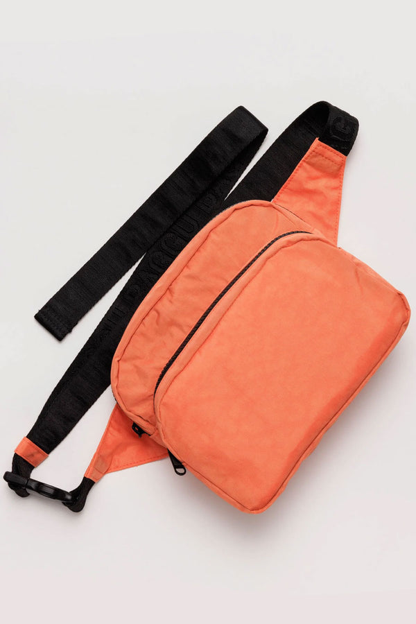 Nylon fanny pack with two main compartments. Fanny pack is bright orange with black straps. White background,