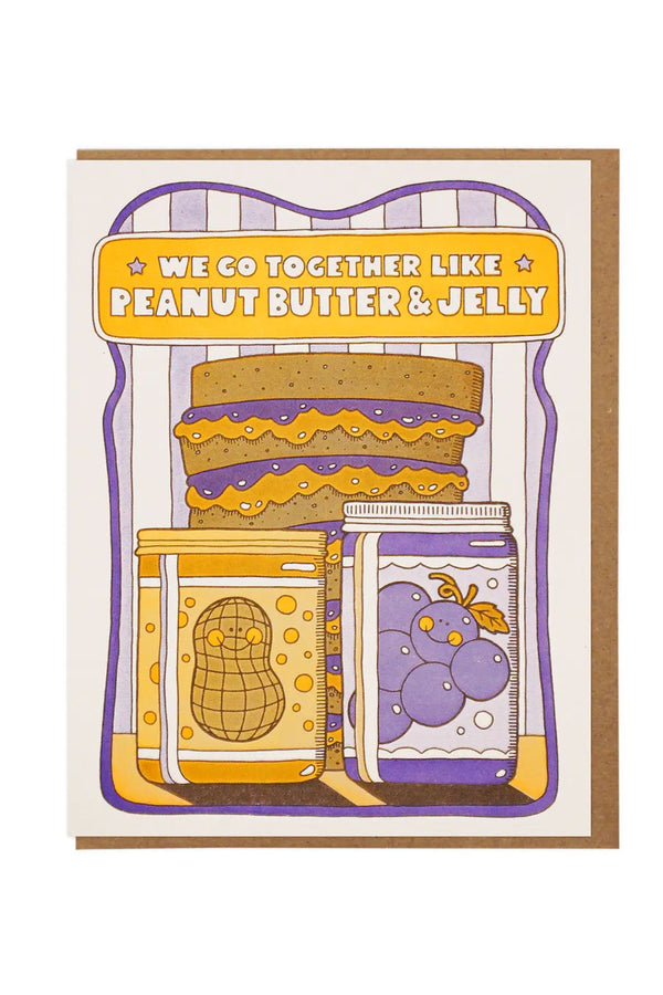 Greeting card featuing a multilayered PBJ sandwich. In front is a jar of peanut butter with a jar of jelly next to it. Above the sandwich the card says We go together like peanut butter and jelly. Surrounding the illustration is a purple border in the shape of a slice of bread. Kraft brown envelope. White background.