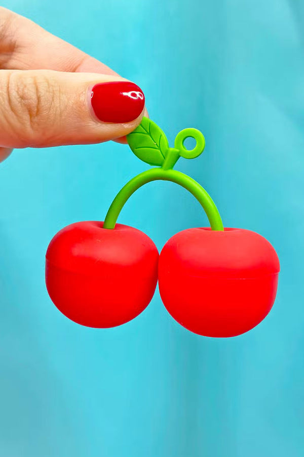 A person holding a small silicone container shaped like cherries on a green stem.