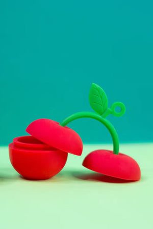 small silicone container shaped like cherries on a green stem. Blue background.