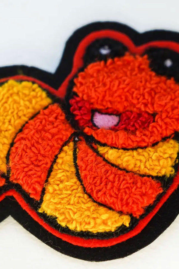 Close up photo of Slimey, a worm character from Sesame Street. The patch is orange and yellow with a pink tongue and black and white eyes. Black border. White background.