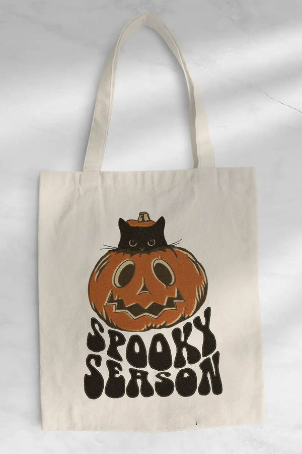 natural cotton tote bag that featuring a jackolantern with a black kitten inside peeking its head out of the top of the pumpkin. Under the pumpkin the tote says Spooky season in large black bubbly letters.