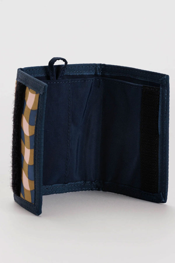 Interior of tri fold wallet. The interior is navy with a key loop. the outside design is a gingham pattern in navy, peach, and gold. White background.