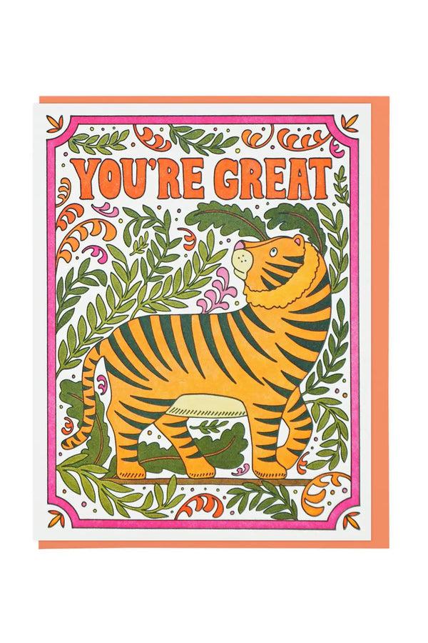 Greeting card of a tiger surrounded by greenery. Above the tiger the card says You're Great. The illustration is inside of a pink border. Orange envelope. White background.