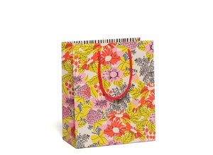 Floral gift bag with red rope handle. The flowers are pink and orange with yellow leaves.