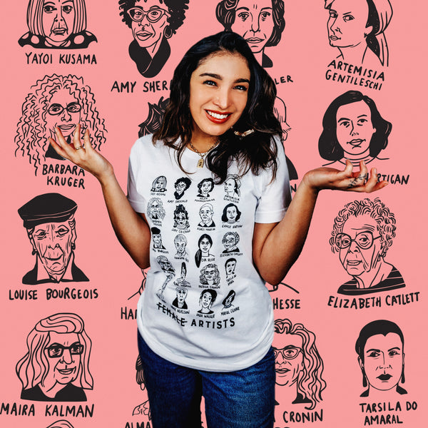 An olive-skinned woman wearing a white tee shirt with illustrated depictions of historically significant female artists.