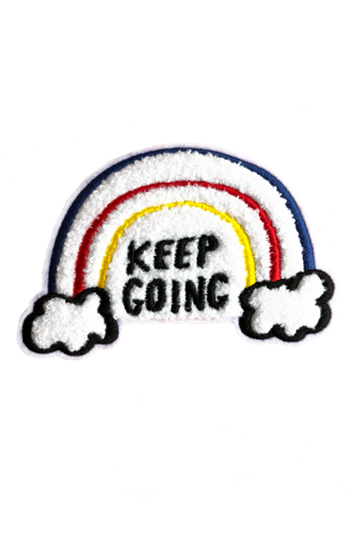 A white chenille patch with embroidered red, blue, and yellow lines forming a rainbow emerging out of clouds. The black embroidered text reads "Keep Going."