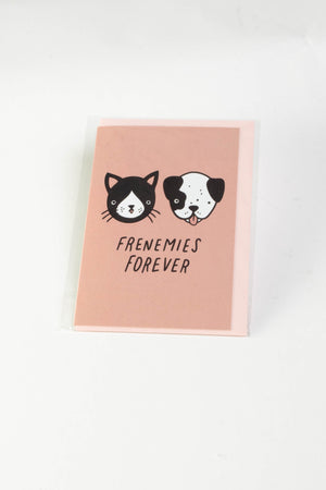 A pale pink greeting card with illustrations of a black and white dog and cat. The text reads "frenemies forever."