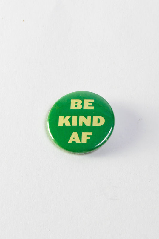 A green pinback button with block letters that read "Be Kind AF."