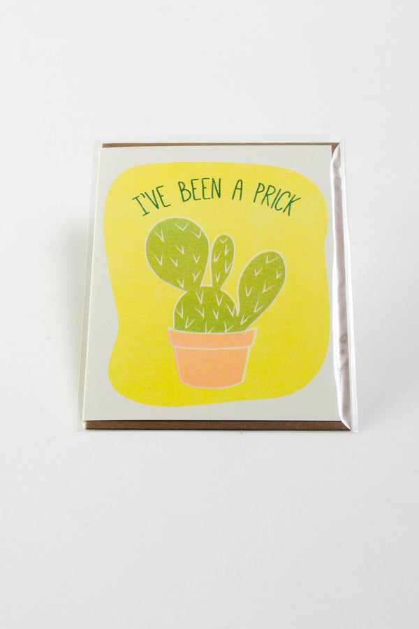 A white greeting card with a yellow background. In the foreground a cactus in a clay pot is flanked by the words "I've been a prick."