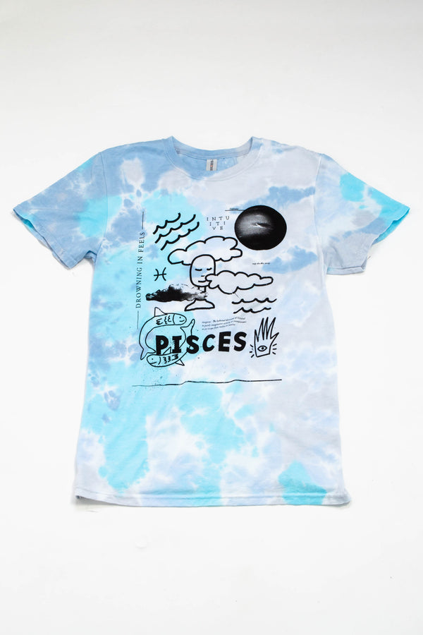 A tie-dye tshirt in multiple shades of blue, grey, and teal. The illustration on the shirt features  a head in the clouds, fish, water, and symbols representing the zodiac sign of Pisces. 