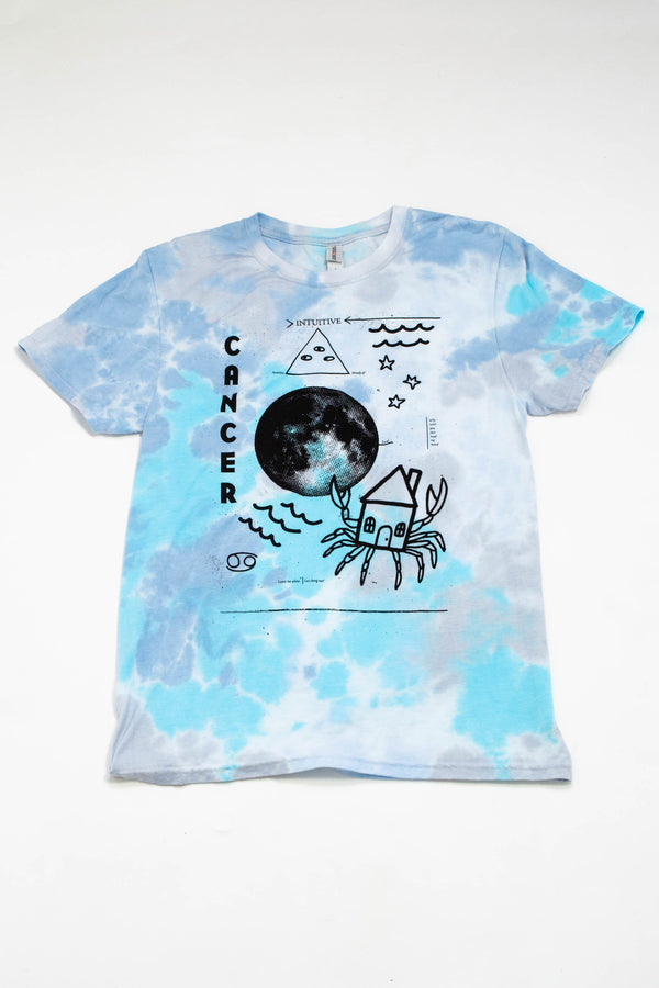 A tie-dye shirt in different shades of blue and aqua with illustrations depicting the astrological sign of "Cancer."