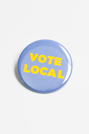 A light blue pinback button with the words "Vote local" in yellow capital letters.