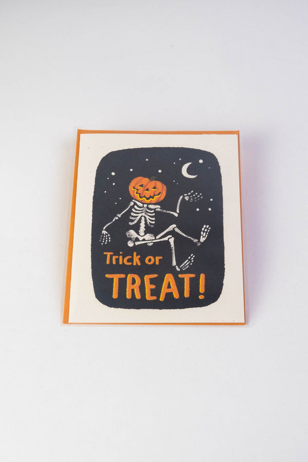 Speckletone card with orange envelope on a white background. The card features a skeleton with a jack-o-lantern head against a black stary night. Under the skeleton in orange lettering the card says Trick or Treat.