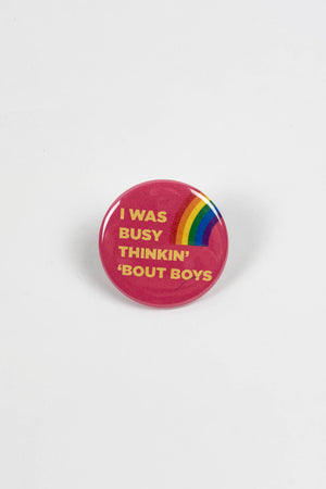 A hot pink pinback button with a small rainbow and yellow text that reads "I was busy thinkin' 'bout boys."