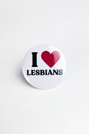 A white pinback button with the black and red text that reads "I heart lesbians." The heart is an image of a red heart.