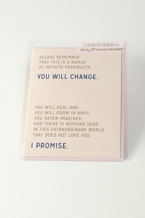 A peach greeting card on a white background. The gold and blue text reads "Please remember that this is a world of infinite possibility. You will change. You will heal and you will grow in ways you never imagined. And there is nothing here in this extraordinary world that does not love you. I promise."
