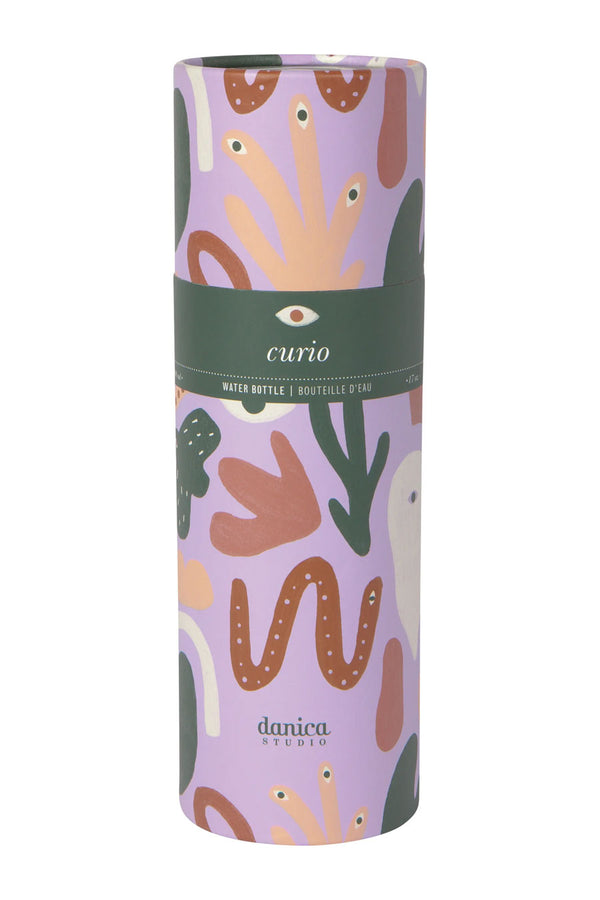 A mauve cardboard cylinder with abstract shapes of birds, eyes, snakes, and plants in various muted greens, oranges, and tan. A Green band across the middle reads Curio Water Bottle with an eye in the middle of the label. White background.