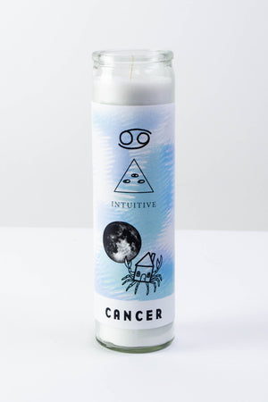 A tall glass votive candle with a sticker depicting symbols for the astrological sign of "Cancer"