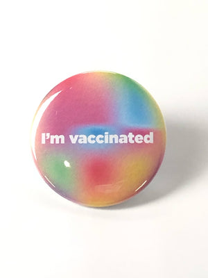 A pinback button with a pastel multicolored background with white text that reads "i'm vaccinated."