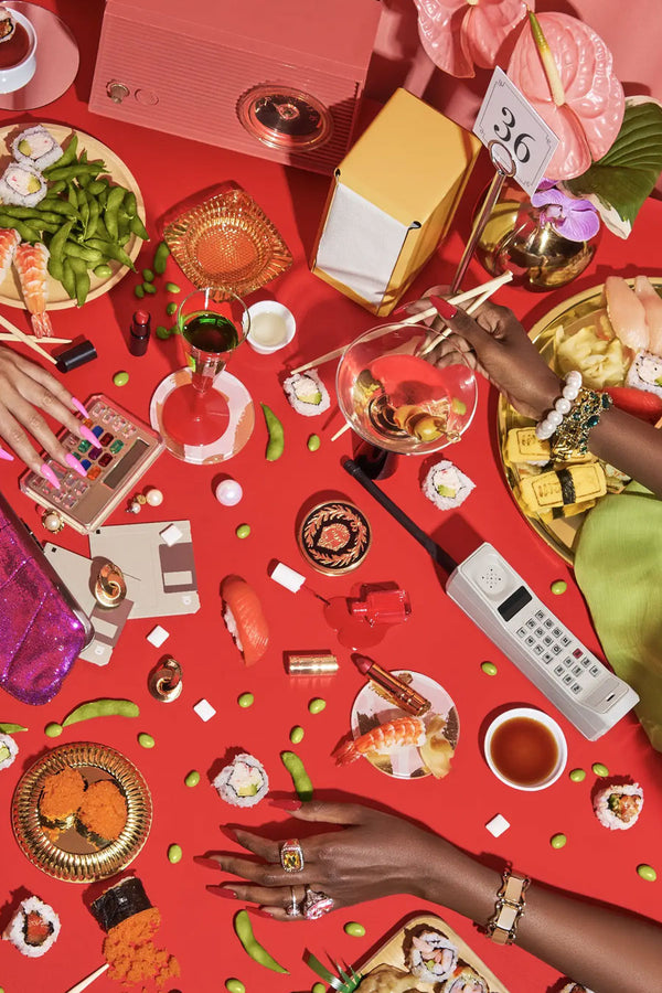 A close up image of the Power Lunch puzzle. The image of a red tabletop with plates of food, calculators, wine glasses, beans, sushi, and cell phones. 