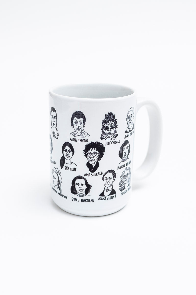 A white mug with illustrations of many historically significant female artists. 