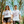Load image into Gallery viewer, Man and woman outside standing in front of small trees under a blue skies. They are wearing white shirts. The tshirt says &quot;The Only Way Out is Through&quot; in pink and black block letters. Surrounding the text are black and pink illustrations of a ladder going through a cloud, a triangle with a crying eye in the middle, a flying bird, a hand and its shadow, a wave, a snake with a knife piercing it, and a dark arched passageway.
