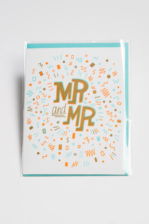 A white greeting card with squiggles and shapes in teal, orange, and gold surround the words "Mr. and Mr."