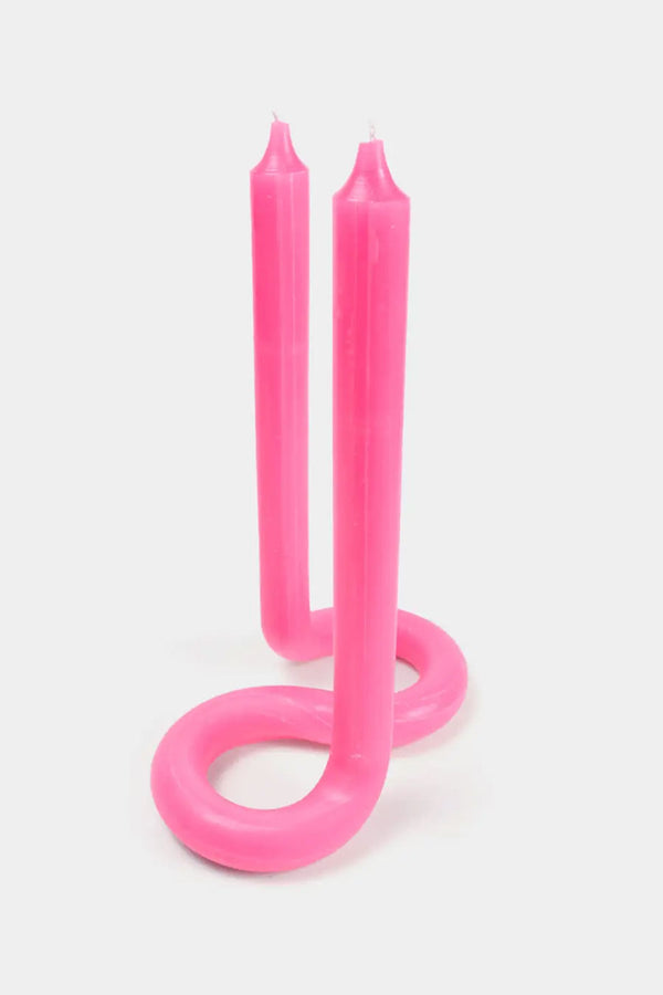 Twisted tall votive candle with wicks at both ends in front of a white background. Candle is pink.